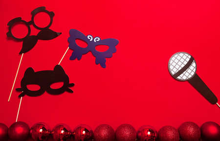 A red color banner with microphone and carnival masks on a stick. A props for entertaining guests at a New Year corporate festive or a karaoke party. An entertainment event - a masquerade.の写真素材