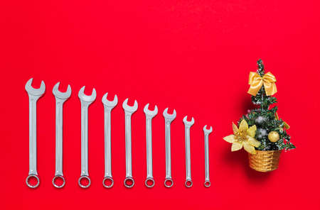 Set of wrenches different size and christmas tree lays on a red background. Banner with tools and...