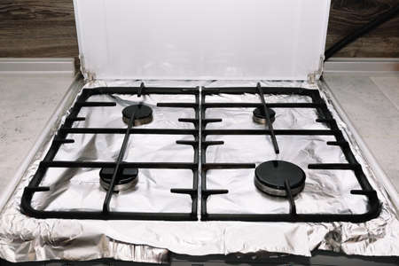Protect the home gas stove from contamination with grease during cooking will help conventional foil. Housewife's secret. Helpful advice on cleaning and cleanliness from a housewife.の写真素材