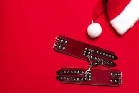 Red color banner with black leather bracers and metal rivets for shackling hands or legs and performing sexual games. BDSM subject. Background for advertising adult products and sex toy store.の写真素材
