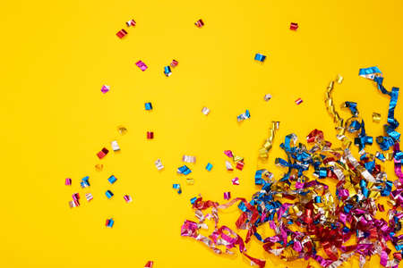 Colorful bright confetti and streamers on yellow background, top view. Copy space for text. Holiday mood, Christmas, New year, birthday or funny party.の写真素材