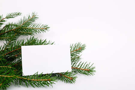 Blank business card with christmas tree branches. New year celebration concept banner. Gift certificate. Side view. Minimalist mockup. Invitation to an event or party. Advertising information.の写真素材