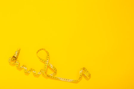 International Women's Day 8 March. World Mother's Day 8 May. Centimeter tape twisted in the shape of the number 8 on yellow background. Greeting card with copy space for text. Hello spring. Close-up.の写真素材