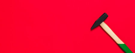 Hammer is isolated on a red background with place for text. Shop banner with construction tools. New Year or Christmas festive backdrop. One of the basic home use instrument for hammering nails.の写真素材
