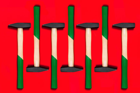 Pattern of hammers isolated on red background. Shop banner with construction tools. New Year or Christmas festive backdrop. One of the basic home use instrument for hammering nails. Building design.の写真素材