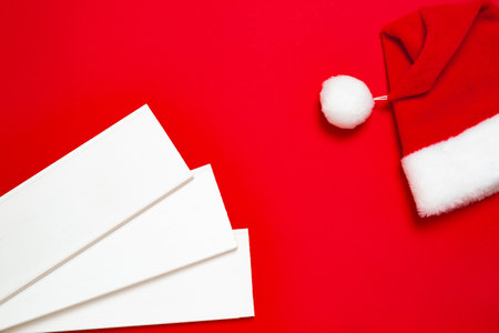 Three white wood planks and Santa Claus hat on a red background. Banner with Christmas or new year mood with a free place for text for a hardware store or art shop or business card.の写真素材