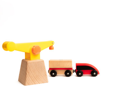 Toy wooden train and crane isolated on white background with copy space, text place. Red locomotive with a wagon. Baby play transport. Childhood. Environmentally friendly good. Toy shop or game store.の写真素材