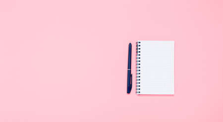 Spiral notepad with blue fountain pen on pink background with copy space, text place. School banner. Stationery shop advertising. Note sheet. Small paper notebook with square lines.の写真素材