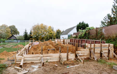 Timber formwork with metal reinforcement for pouring concrete and creating a solid foundation for a building. Construction site and process. Private building business. Warm season. Countryside. Work.の写真素材