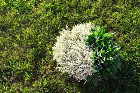 A huge bouquet of flowers on a green lawn with copy space, text place. A large basket of white...