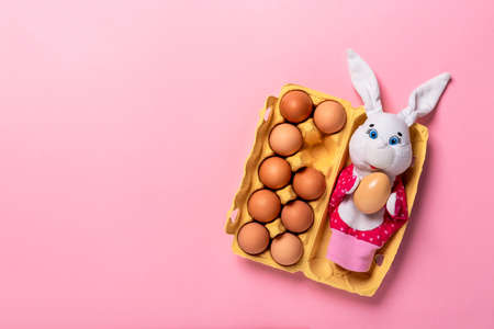 Banner with Easter bunny laying in the yellow packing with ten eggs on pink background with copy...