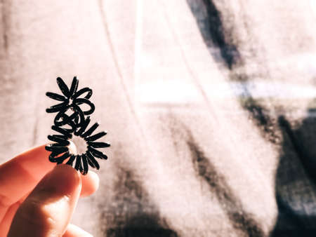 The hair tie as a black coil spring is twisted in shape of the number eight and lay in hand. Holiday...