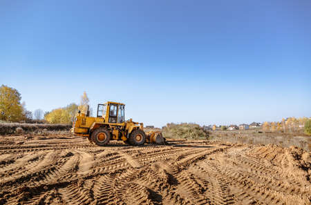 large yellow wheel loader aligns a piece of land for a new building. Preparation of the land for the...