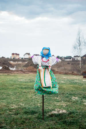 Shrovetide. Big beautiful doll in national dress. Symbol of Pancakes week, scarecrow for burning. Winter end and spring coming. Slavic traditional - Maslenitsa. Green grass. Pagan rite. Outdoor feast.の写真素材