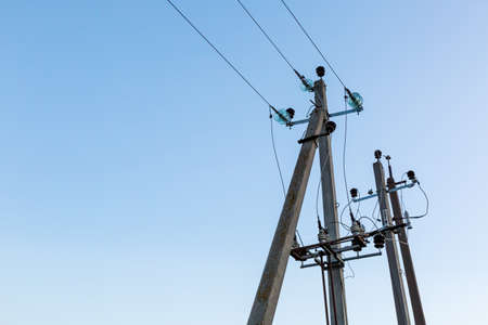 Concrete poles with high voltage wires. Against the background of a blue sky with copy space. Power lines. Supply of electricity, internet and communication. Engineering network. Industrial facility.の写真素材