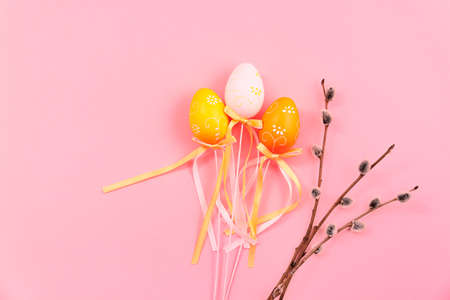 Banner with plastic eggs in satin ribbon bows and branch of pussy willow. Happy easter card with holiday symbol. Place for text. Mockup design. Copy space. Pink orange and yellow colors. Three things.の写真素材