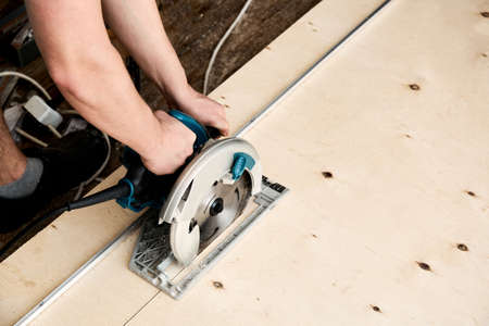 Sawing plywood by circular saw. Home repair.