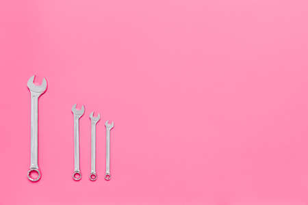 Four metal wrenches of different sizes isolated on pink background with copy space. Conceptual idea of the differences between: boss and employee, older and younger, big and small, parent and child.の写真素材