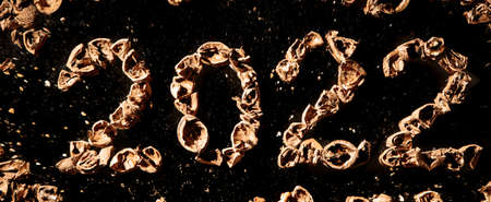 2022 new year. Numbers made from a pile of nutshells. Food style calendar. Wallpaper. Banner. Brown color walnut texture. Signed two and zero. Flat lay mockup design. Business card. Black background.の写真素材