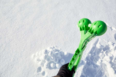 A children toy is a tool for modeling snowballs from snow. Green color plastic device. Winter...