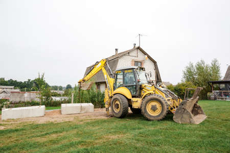 Wheel loader. Excavator install the foundation blocks into a trench. Retaining wall building. Construction site. Workers manage installing. Full HD footage video. Semkovo, Belarus - September 3, 2021.のeditorial素材