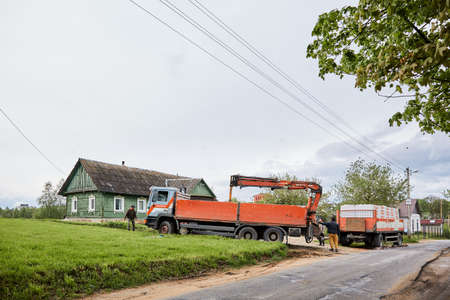 Truck with trailer delivered blocks to construction site and unloads a cargo by hydraulic...