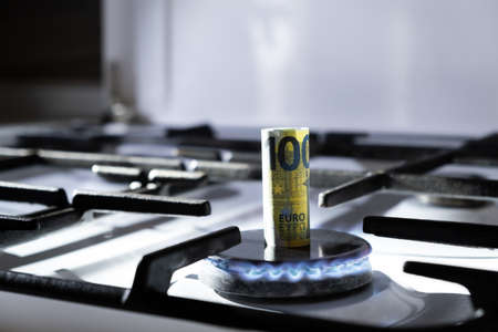 Concept of gas crisis. 100 euro bank note is burning on kitchen stove. Cash money. High prices of natural resources. Blue flame. Utility debt. Number hundred. Energy war. Saving home budget. Financeの写真素材