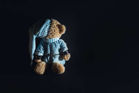 Toy bear is kneeling, facing the wall, hands behind his back in handcuffs. Child abuse. Abduction of children. Slavery and the sale of people. Psychological violence in the family, society and school.の写真素材