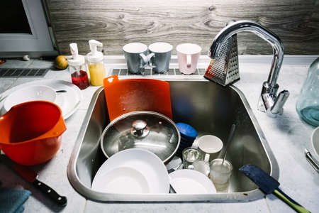 4K. A pile of dirty dishes on the table and in the kitchen sink. Plates in leftover food. Routine homework. Cleaning concept after guests. A very unkempt house. Nobody. Sloppy look. video footage.の写真素材