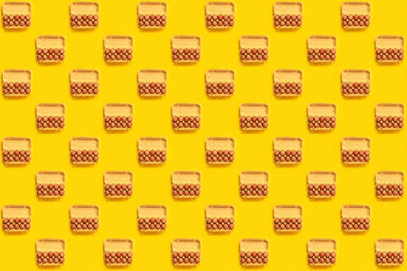 Seamless pattern. Natural organic chicken eggs in cardboard package isolated on yellow background, top view, copy space. Food banner. Business card of grocery store. Fresh eco farm product. Textureの写真素材