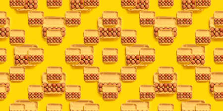 Seamless pattern. Natural organic chicken eggs in cardboard package isolated on yellow background, top view, copy space. Food banner. Business card of grocery store. Fresh eco farm product. Textureの写真素材