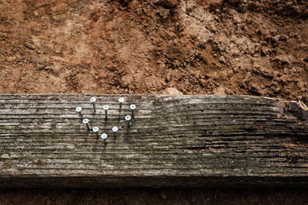 Nails in the shape of heart hammered into wood plank. Postcard for a Valentine or Father Day....