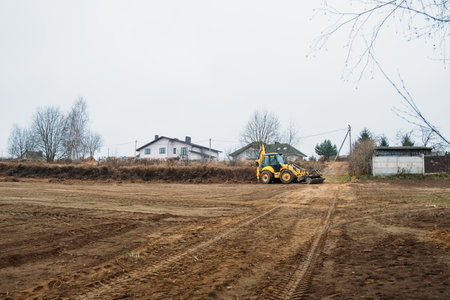 Tractor levels field. Backhoe loader clearing construction site. Bulldozer prepares building ground....