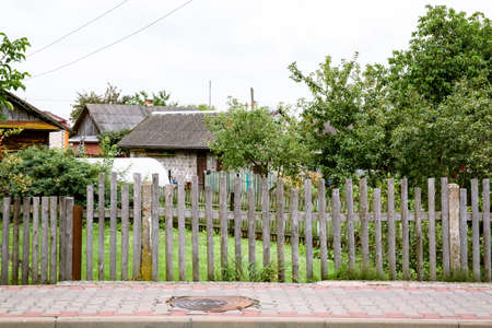 old wood fence. construction side. summer season. Transparent wooden hedge. Unfinished building. Poor area.の写真素材