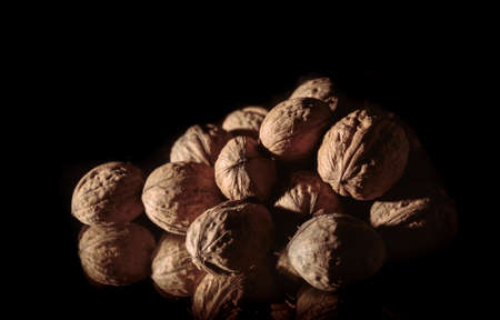 A walnuts heap close-up. Copy space. Beautiful still life on a dark background. Healthy food. Ingredient. Useful brain nutrients. Nut is a tasty diet snack. Brown color. Wallpaper. Photo art. Banner.の写真素材