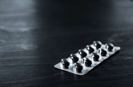 Black pills are on the table. copyspace. close-up. Blister with medicine. treatment tablets. Pharmacology concept. dietary supplements. Daily health help. Banner. medical industry. Empty text place.の写真素材
