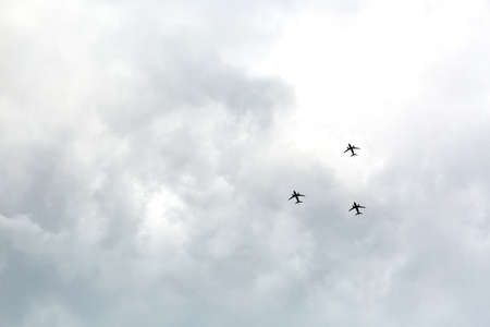 airshow. Three planes fly across the sky in the same direction. flight training. cloudy weather. Bad visibility. sky in clouds. military airplanes. passenger transport. copyspace. Number 3. Up view.の写真素材
