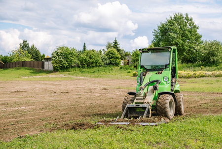 A green mini skid steer loader clear the construction site. Land work by the territory improvement....