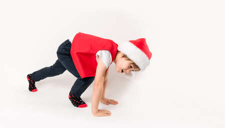 Portrait of happy child on the start in Santa Claus hat isolated in white background. A 5 year European boy looks at the camera. Banner. copyspace. Before jump. Concept of New Year gift certificate.の写真素材