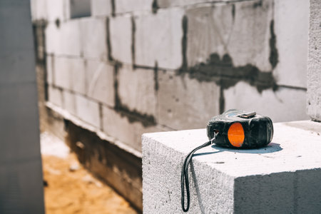 The tape measure lies on a gas silicate block close-up. construction site. copyspace. The concept of technical supervision and measurement of completed construction stages of work. building material.の写真素材