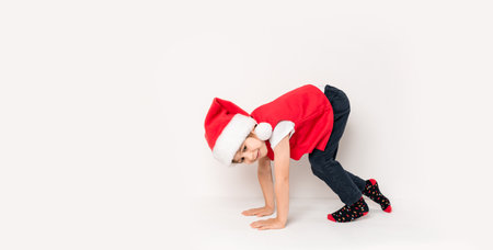 Portrait of happy child standing on the start in Santa Claus hat isolated on white background. 5 year European boy starting run a marathon. Banner. copyspace. Concept of New Year gift certificate.の写真素材