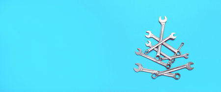 Christmas tree made of wrenches on a blue background. New Year banner with tools. Postcard with place for greeting text for happy new year with industrial holiday concept. close-up.の写真素材
