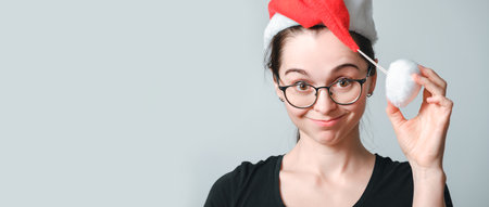 Portrait of smiling 30 year old woman wearing glasses and Santa Claus hat. New Year holiday certificate concept. Young happy cheerful girl. beautiful smile. Festive mood. Close up female face. business card.の写真素材