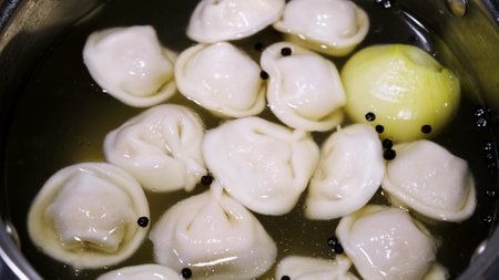 Meat dumplings are boiling with a broth in a pot. Pelmeni are the traditional national Russian cuisine. Italian ravioli. Semi-finished food. Ready dish. Concept of fast tasty family dinner cooking.の写真素材