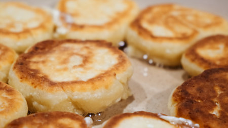 Cheesecakes are flying on a pan. Cheese pancakes. cooking process. Tasty breakfast. food for children. The dish of curd. Traditional Russian cuisine. olive oil. Bubbles of hot sunflower oil.の写真素材