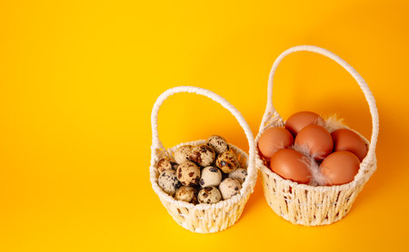 Two white handmade straw basket full of hen and quail eggs on yellow background. copyspace. Empty text place. easter holiday card. springtime mockup design. health food product. farm production.の写真素材