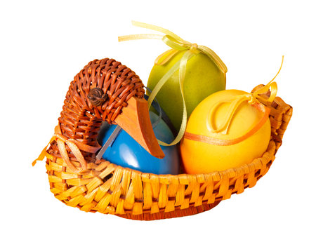 easter decor. Handmade duck shaped straw basket with colorful painted eggs in satin bows and ribbons. cut out. Interior decoration detail. side view. close-up. isolated object. Straw weaving hobby.の写真素材