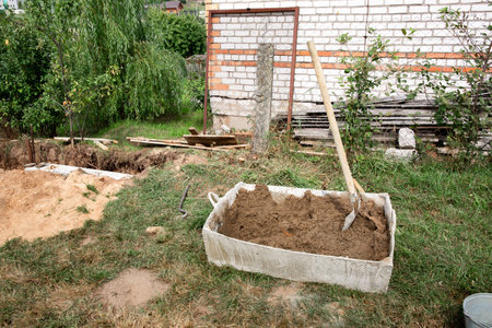 specific preparation. Construction site with a container full of sand for the preparation of cement mortar. Shovel. building tools. construction equipment.の写真素材