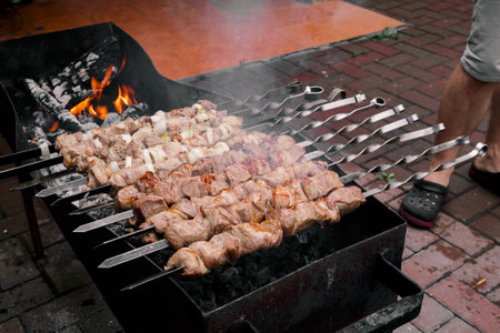 Marinated meat with onion, food cooking on skewers on fire. Preparing pork shashlik on a charcoal mangal. beef grill. BBQ. side view. outdoor picnic. Traditional tasty shish. Juicy meal. close-up.の写真素材