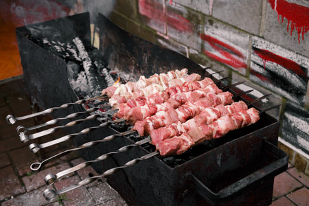Marinated meat with onion, food cooking on skewers on fire. Preparing pork shashlik on a charcoal mangal. beef grill. BBQ. side view. outdoor picnic. Traditional tasty shish. Juicy meal. close-up.の写真素材